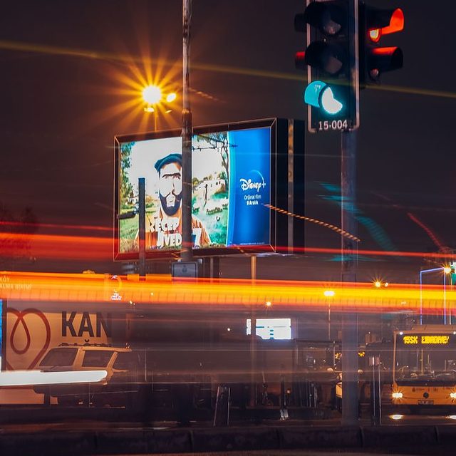 A city street at night with a lit billboard