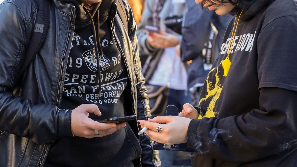 Friends on a busy street looking at their phones together