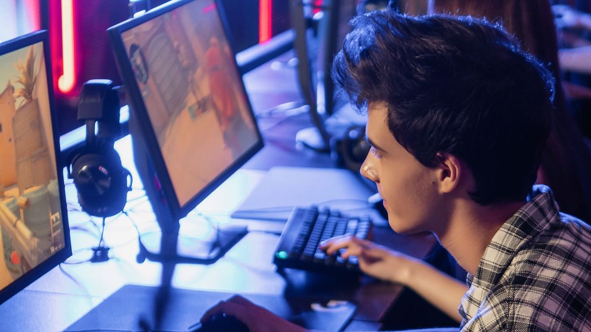 A young gamer at a lit-up PC in a gaming room